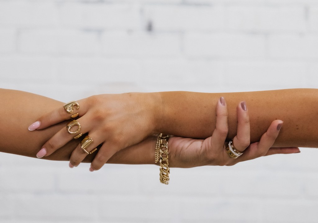 Tanned hands joined together with SOL rings on fingers