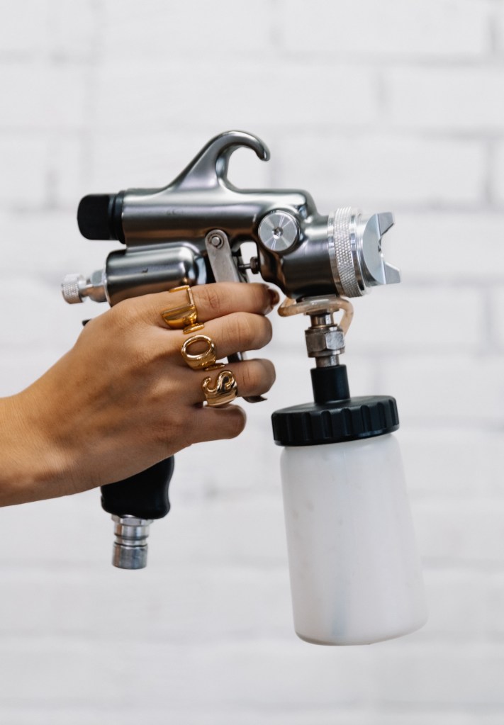 Hand holding spray tan gun 